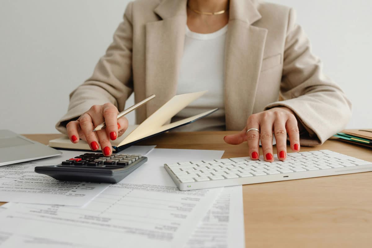 Mujer trabajando con documentos y su calculadora para hacer procesos tributarios - Seven asesorías tributarias